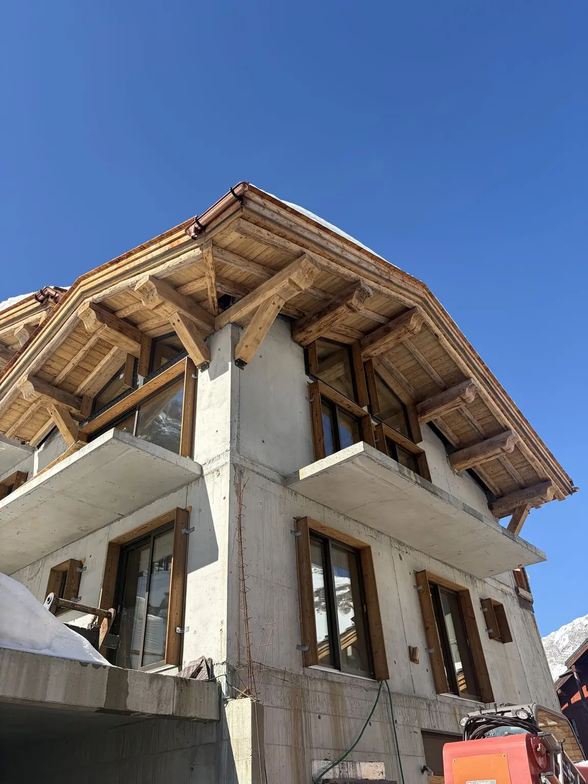 Maison chalet : charpente bois apparente en débord, balcons et menuiseries bois.