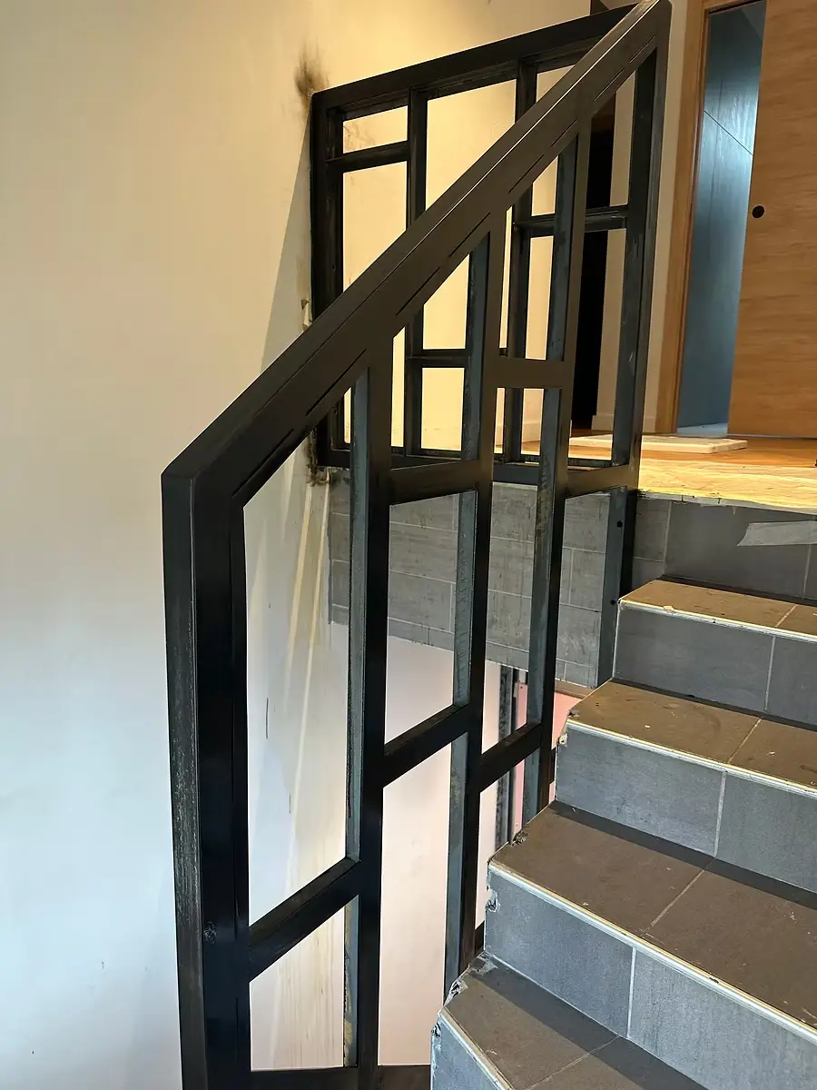 Garde-corps en acier noir le long d’un escalier intérieur.