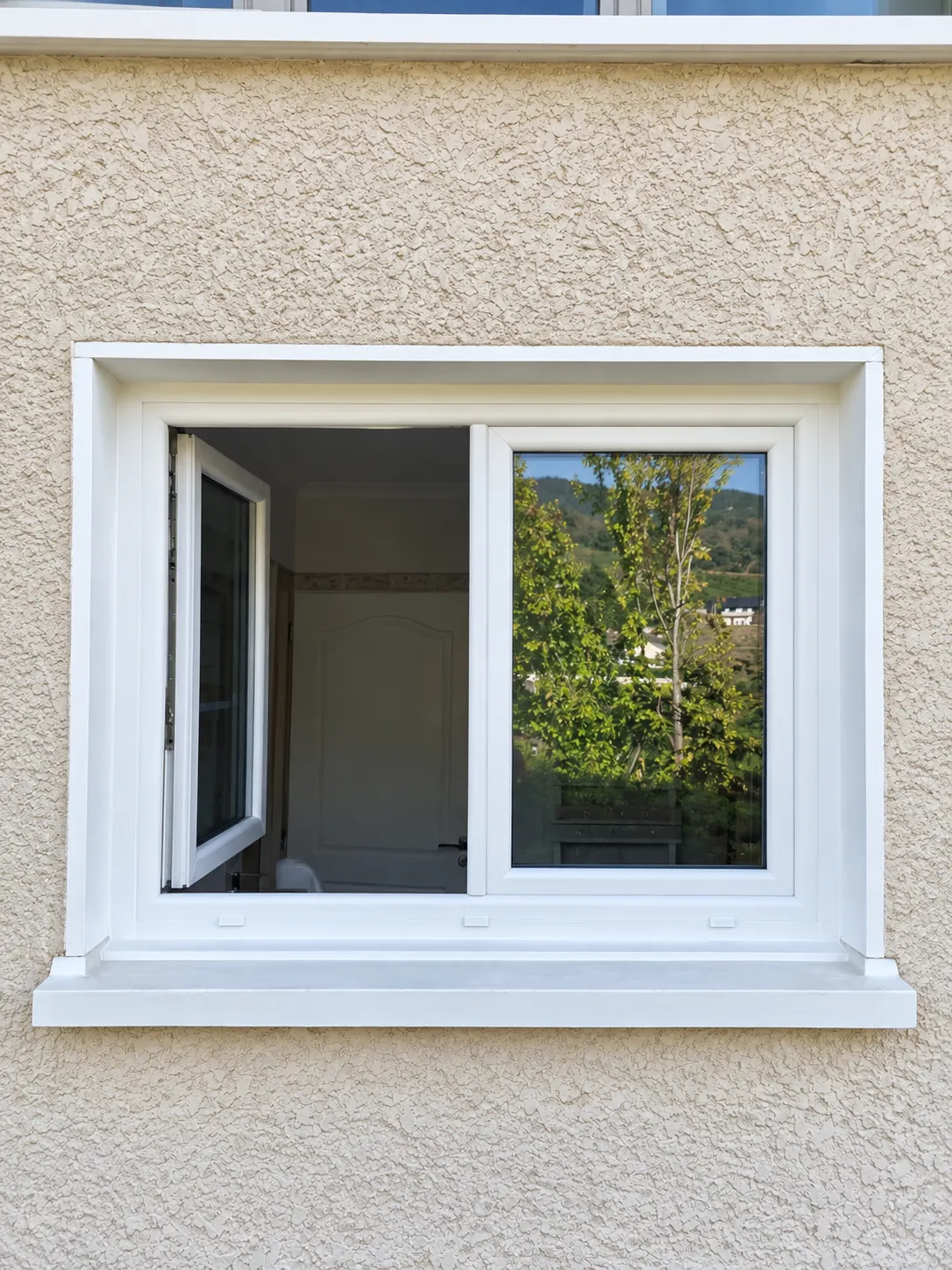 Fenêtre blanche à deux vantaux sur une façade crépie.