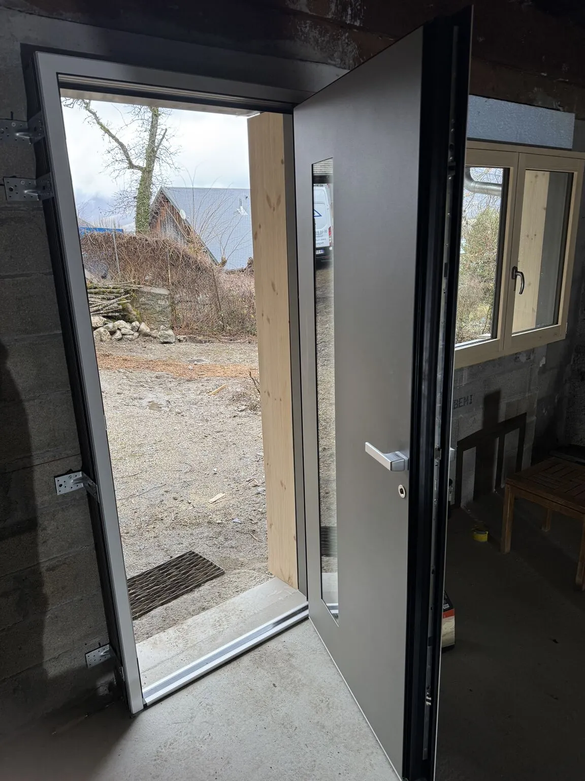 Porte d’entrée grise ouverte, vue de l’intérieur pendant le chantier.