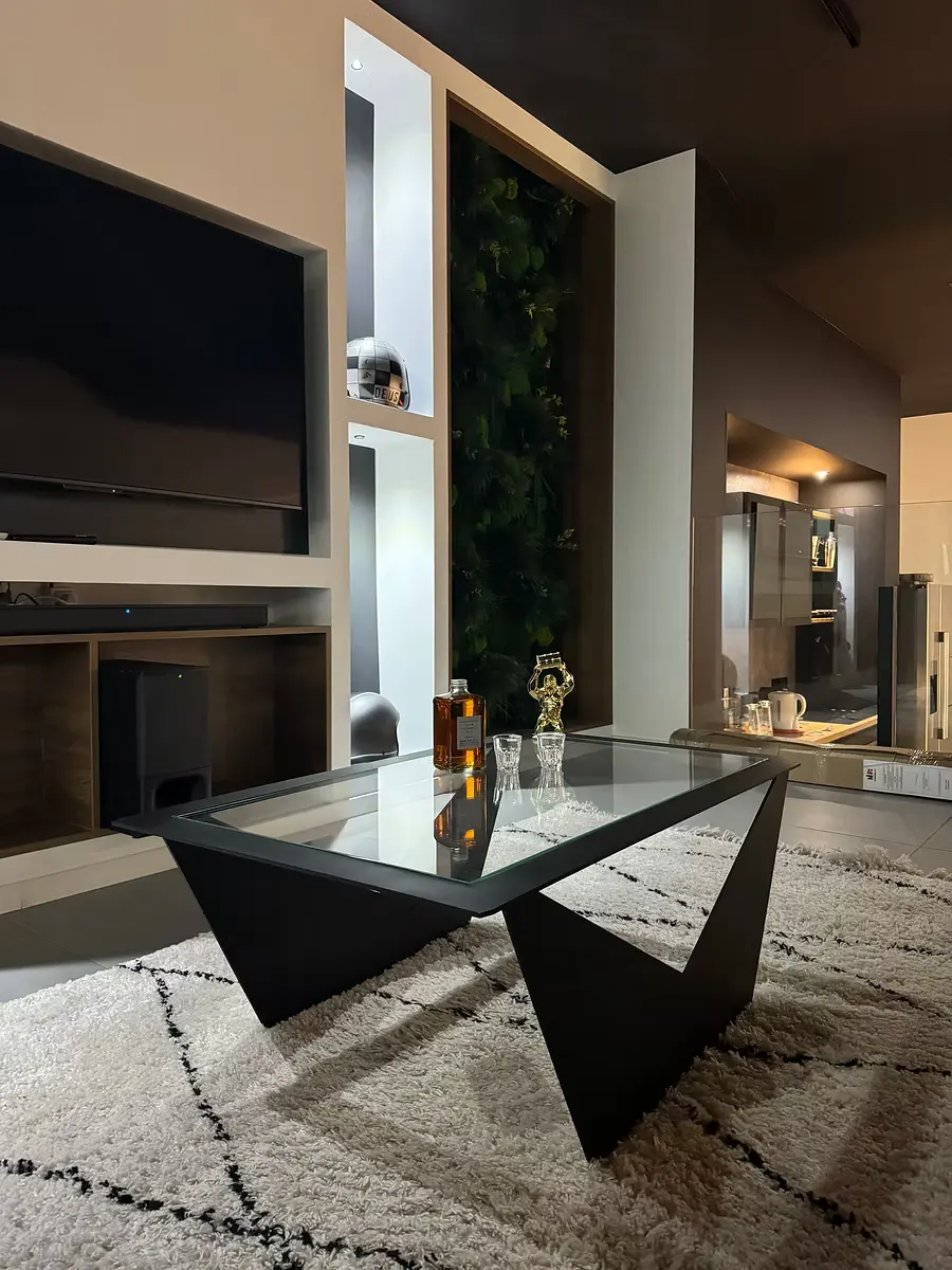 Table basse au piètement en acier noir et plateau en verre, dans un séjour.
